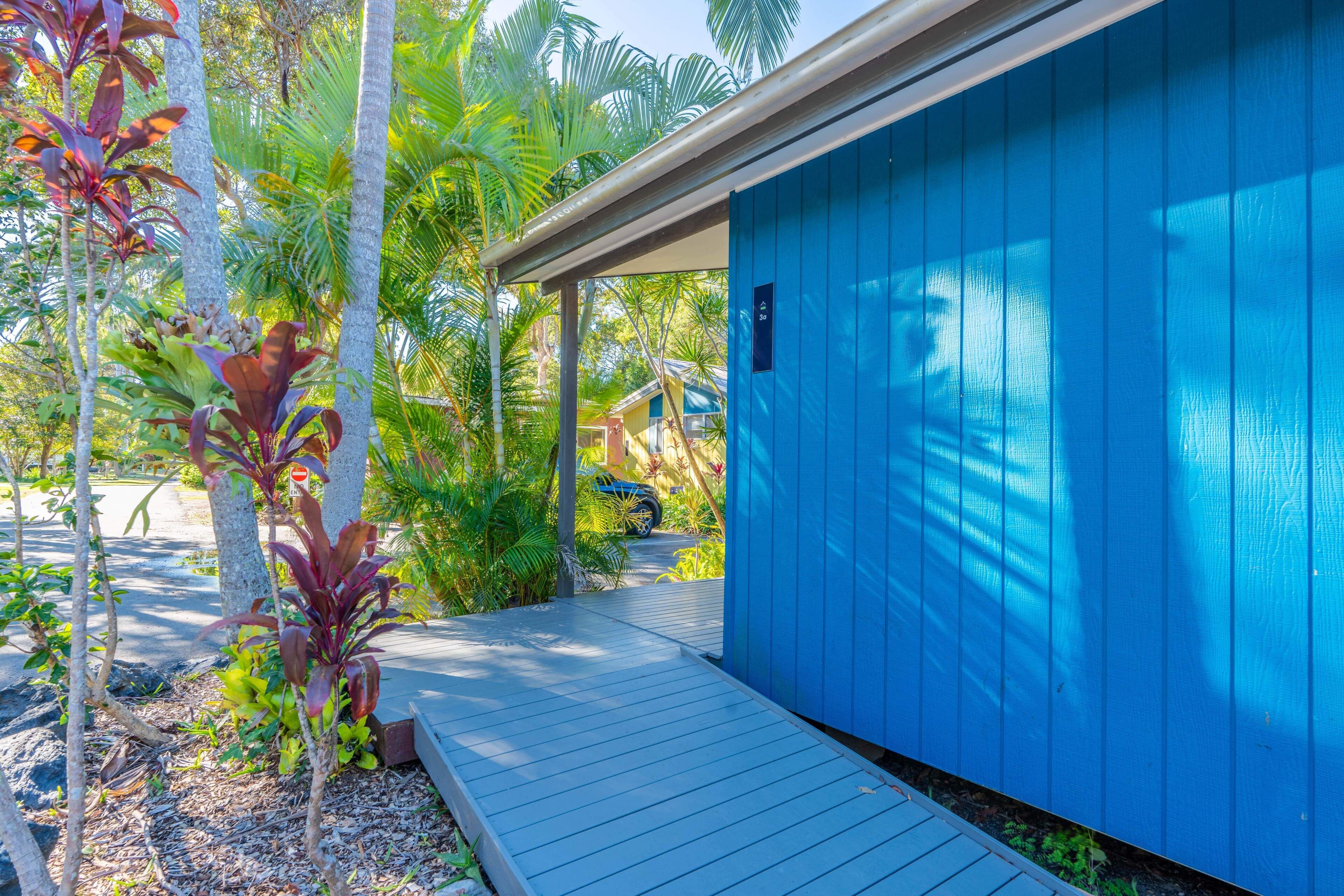 A blue building with a covered porch and a wooden deck.