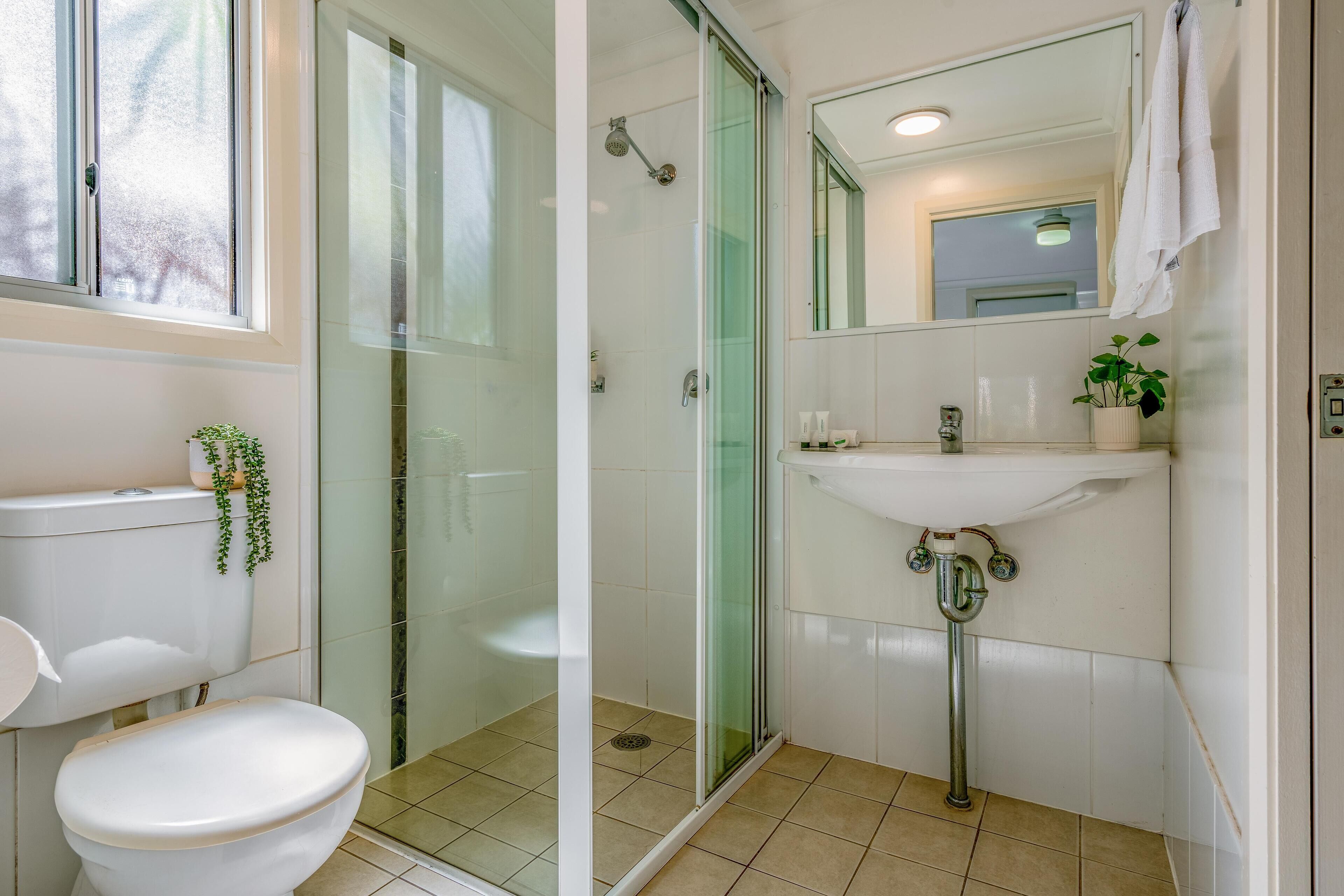 Une salle de bain moderne équipée de toilettes, d’un lavabo et d’une douche à parois de verre.