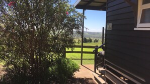 Una cabaña de madera con un porche cubierto y vistas a un campo verde, con un letrero que dice "The Cottage".