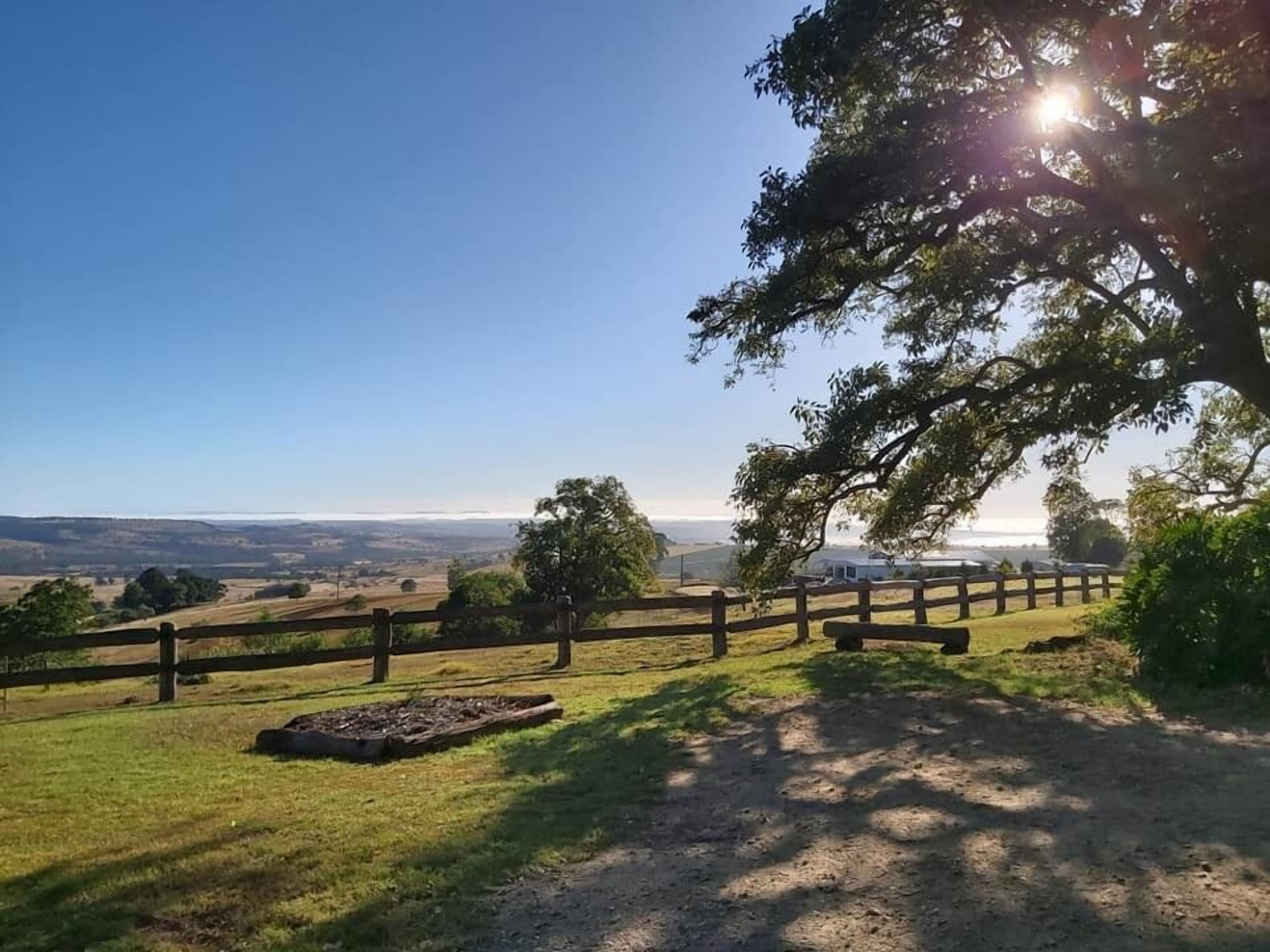 A fenced outdoor area with a clear view of distant hills and a body of water.