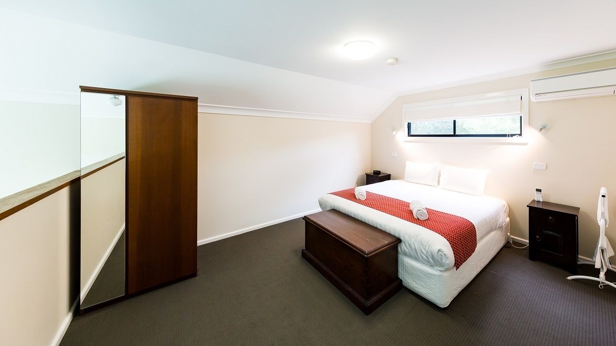 Une chambre à coucher comprenant un lit, une table de chevet, une commode et une armoire en bois.