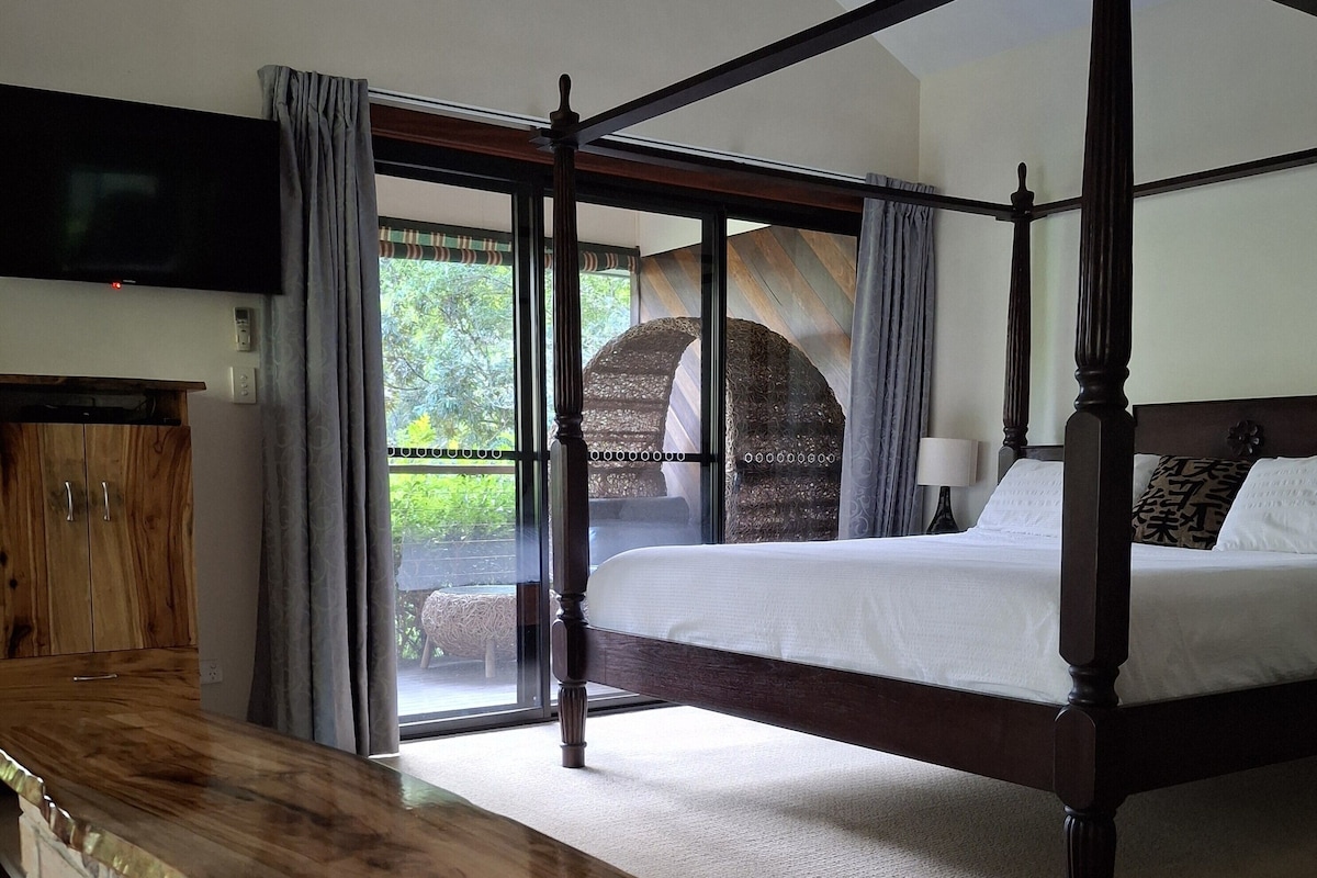 Uma cama com dossel com vista para o exterior, um armário de madeira e uma parede de pedra.