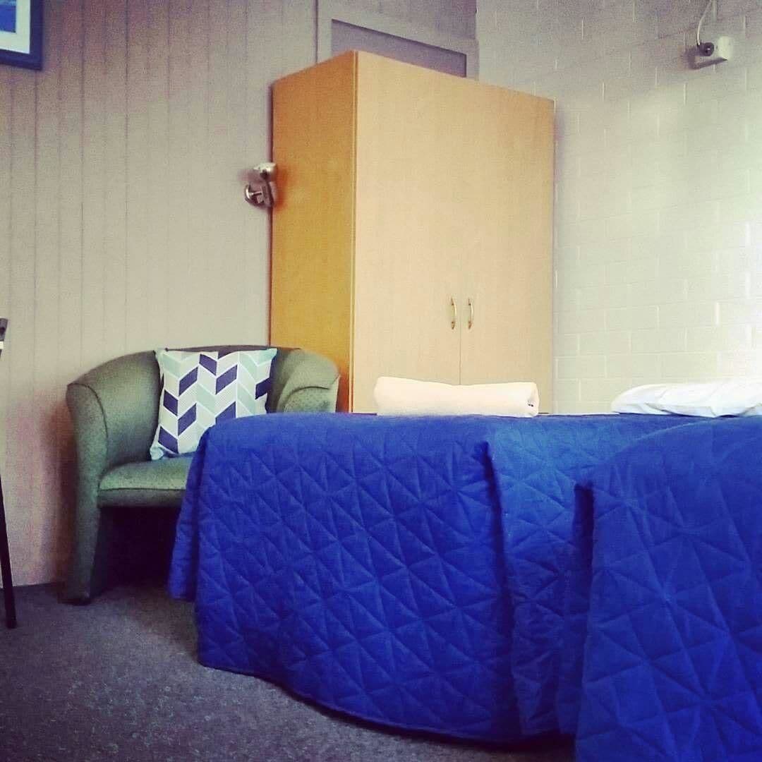 A room with a bed, a green armchair, and a wardrobe.