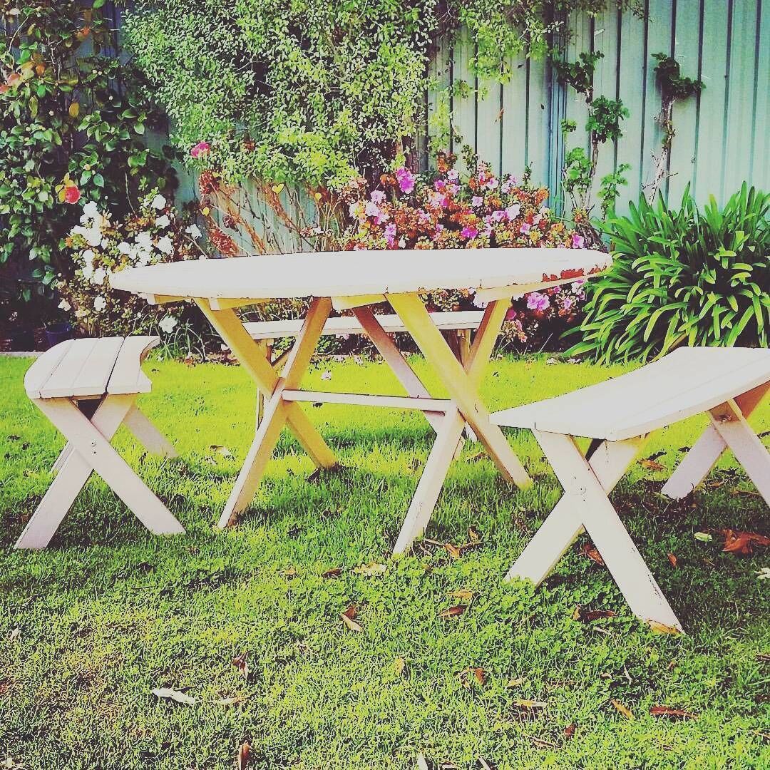 A wooden picnic table with benches in a garden.