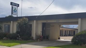 Een motel met een overdekte ingang, een bord dat een kamer beschikbaar geeft, en een bord voor Town Central Motel.