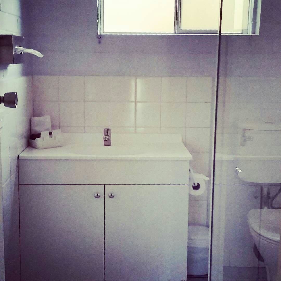 Een badkamer met een wit wastafel, toilet en douche.