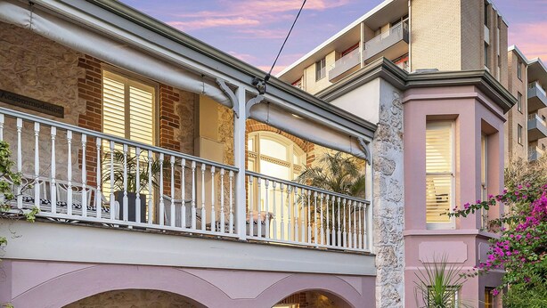 Un immeuble à plusieurs étages doté d’un balcon, d’arcs en pierre et d’une enseigne portant l’inscription « Arundels ».