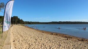 Ein Strand mit einer Flagge, blauem Himmel und ruhigem Wasser.