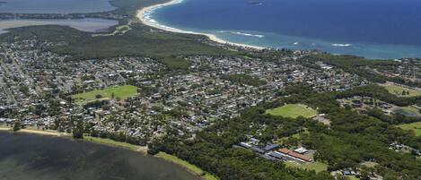 An aerial view of a coastal town with a beach, residential areas, and a large body of water.