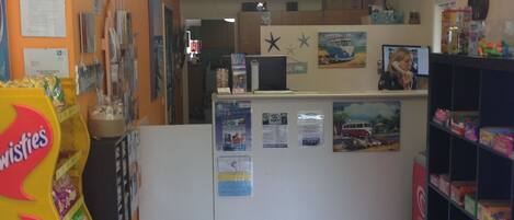 A reception area with a counter, a telephone, and a wall with various posters and decorations.
