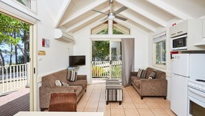 Ein geräumiger Wohnbereich mit zwei Sofas, einem Couchtisch, einem Fernseher und einer Küche mit Mikrowelle und Backofen.