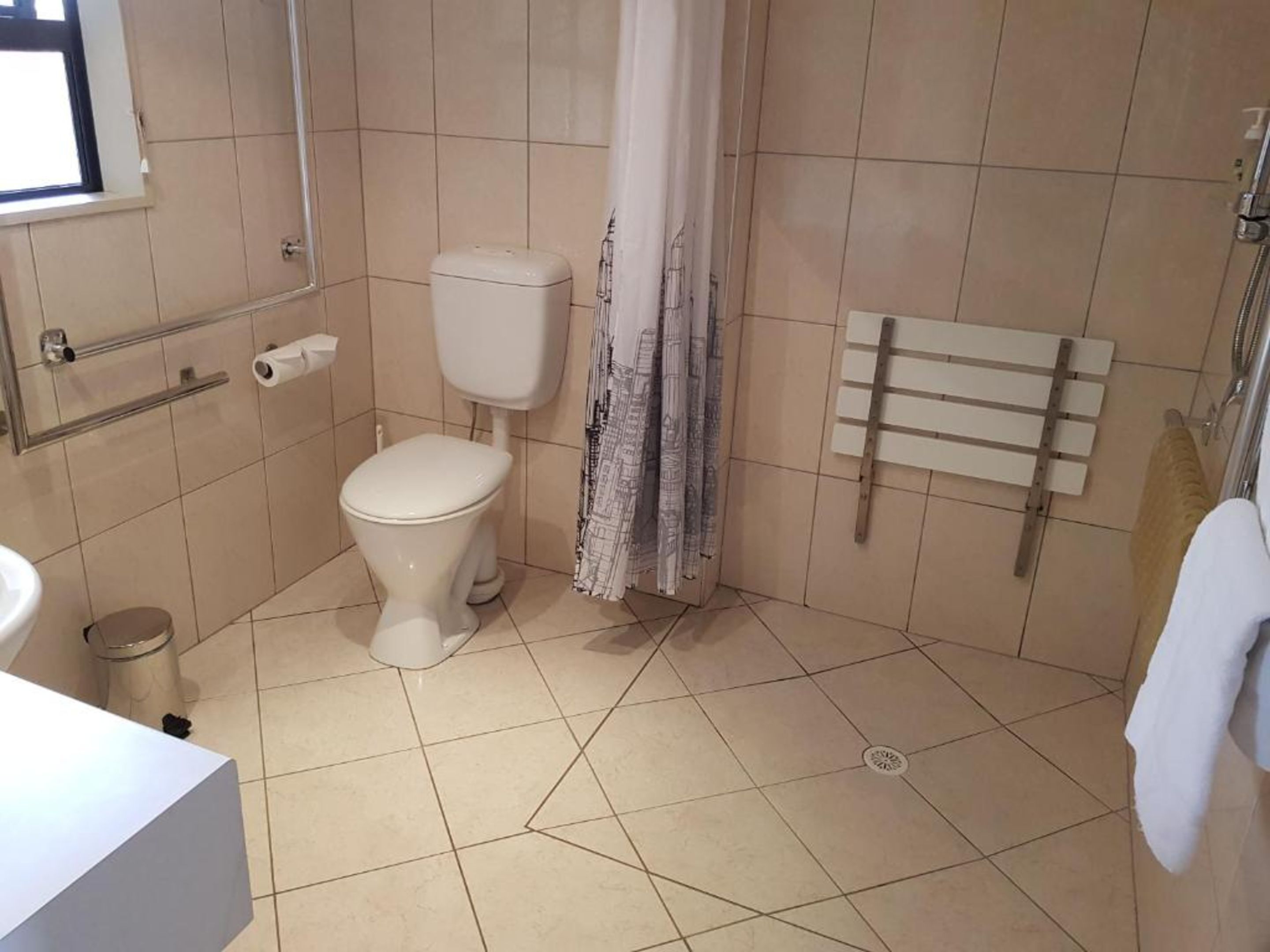 A bathroom with a toilet, a shower, and a sink.