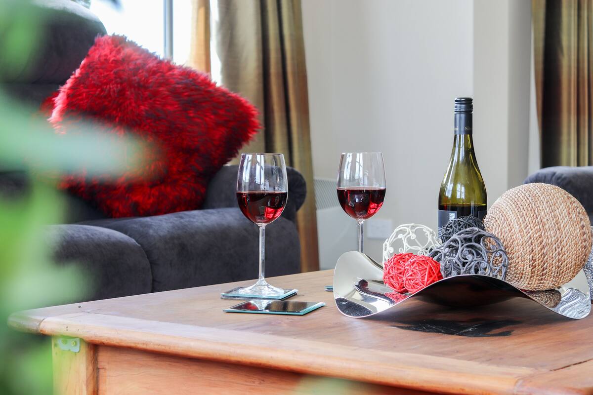 A wooden table with two wine glasses, a wine bottle, and decorative items.