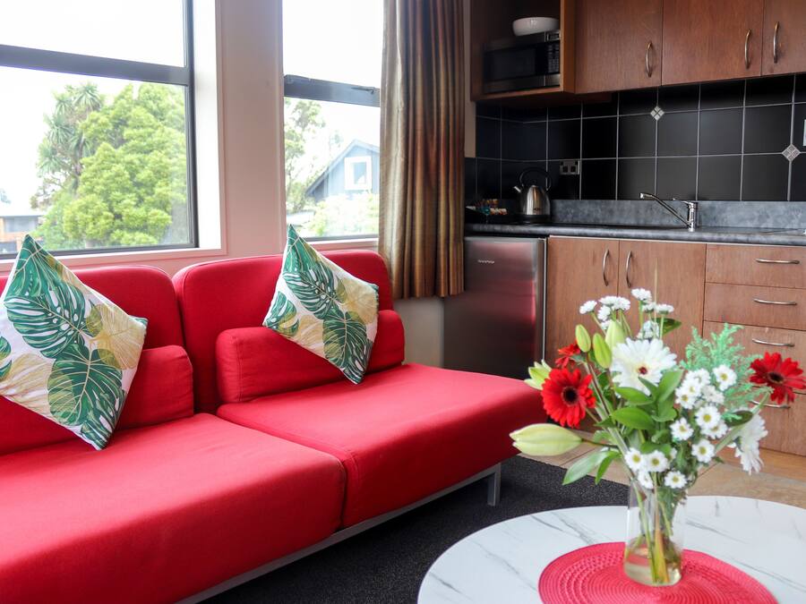 Una sala de estar moderna con un sofá rojo, una mesa de centro blanca y un jarrón de flores.