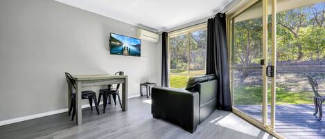 Un salon moderne comprenant un coin repas, un canapé et une grande porte-fenêtre coulissante donnant sur une terrasse.