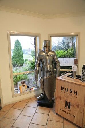 A statue of a knight in armor next to a wooden counter labeled "RUSH ROASTING CO NITRO COFFEE".