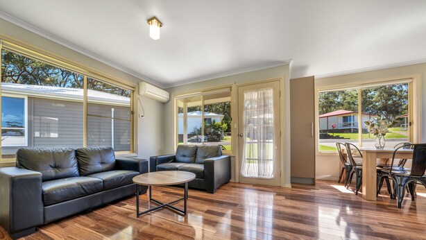 A spacious living room with a sectional sofa, a round coffee table, and a dining area with chairs.