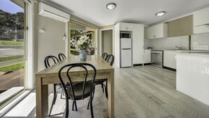 A modern kitchen with white cabinets, a wooden dining table, and chairs.