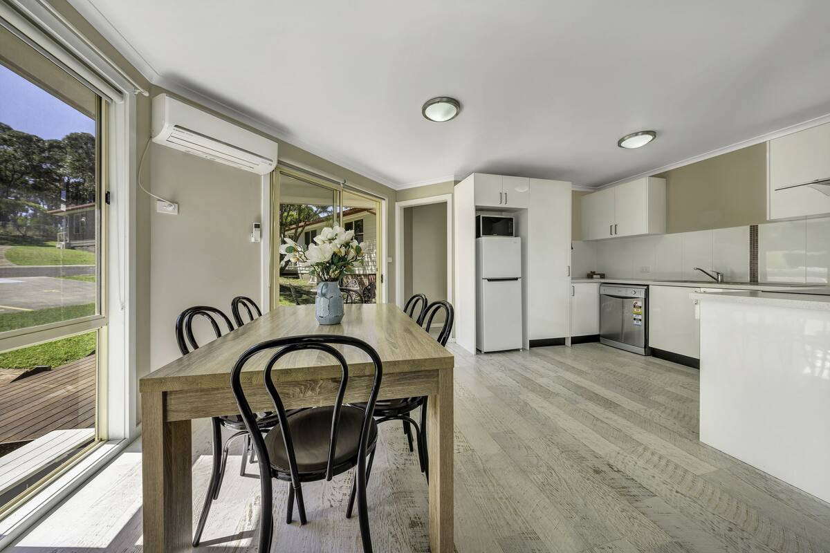 Una cocina moderna con armarios blancos, una mesa de comedor de madera y sillas.