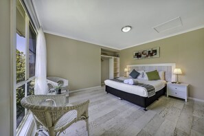 A bedroom with a bed, nightstands, a chair, and a closet.