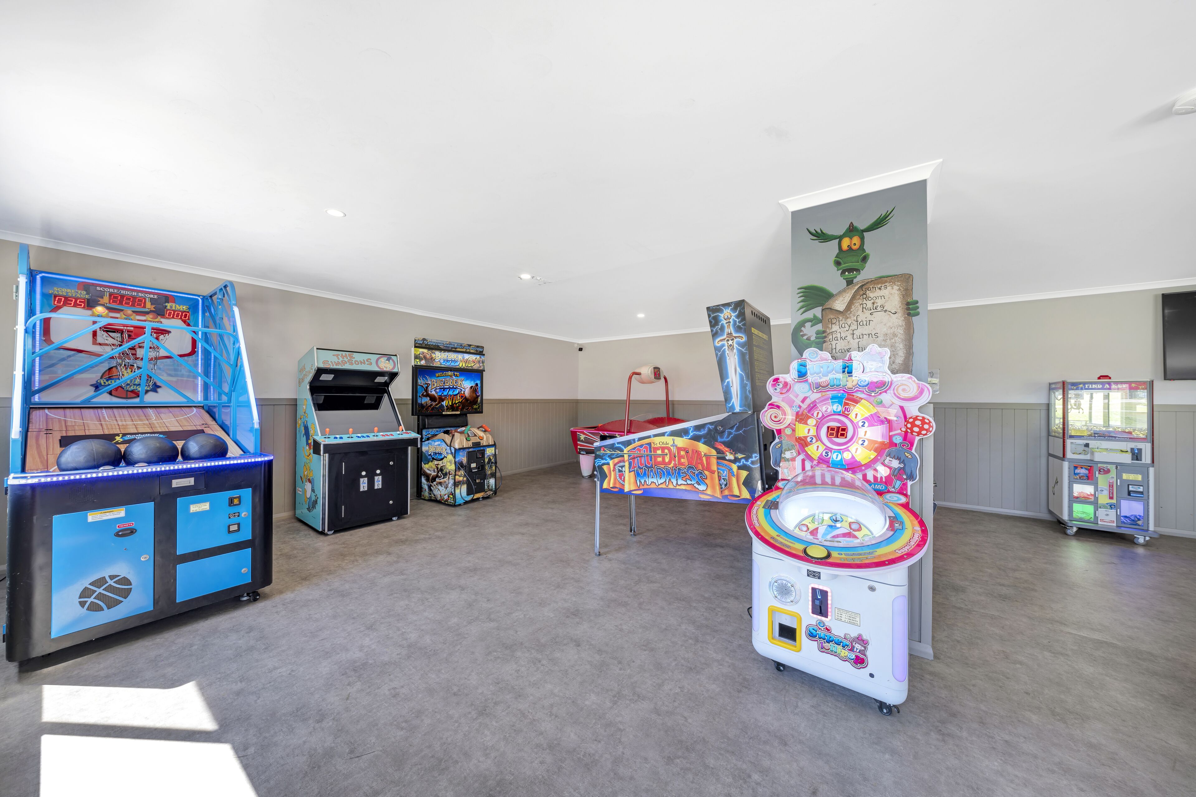 Una habitación con juegos de arcade, un aro de baloncesto y un cartel en la pared.