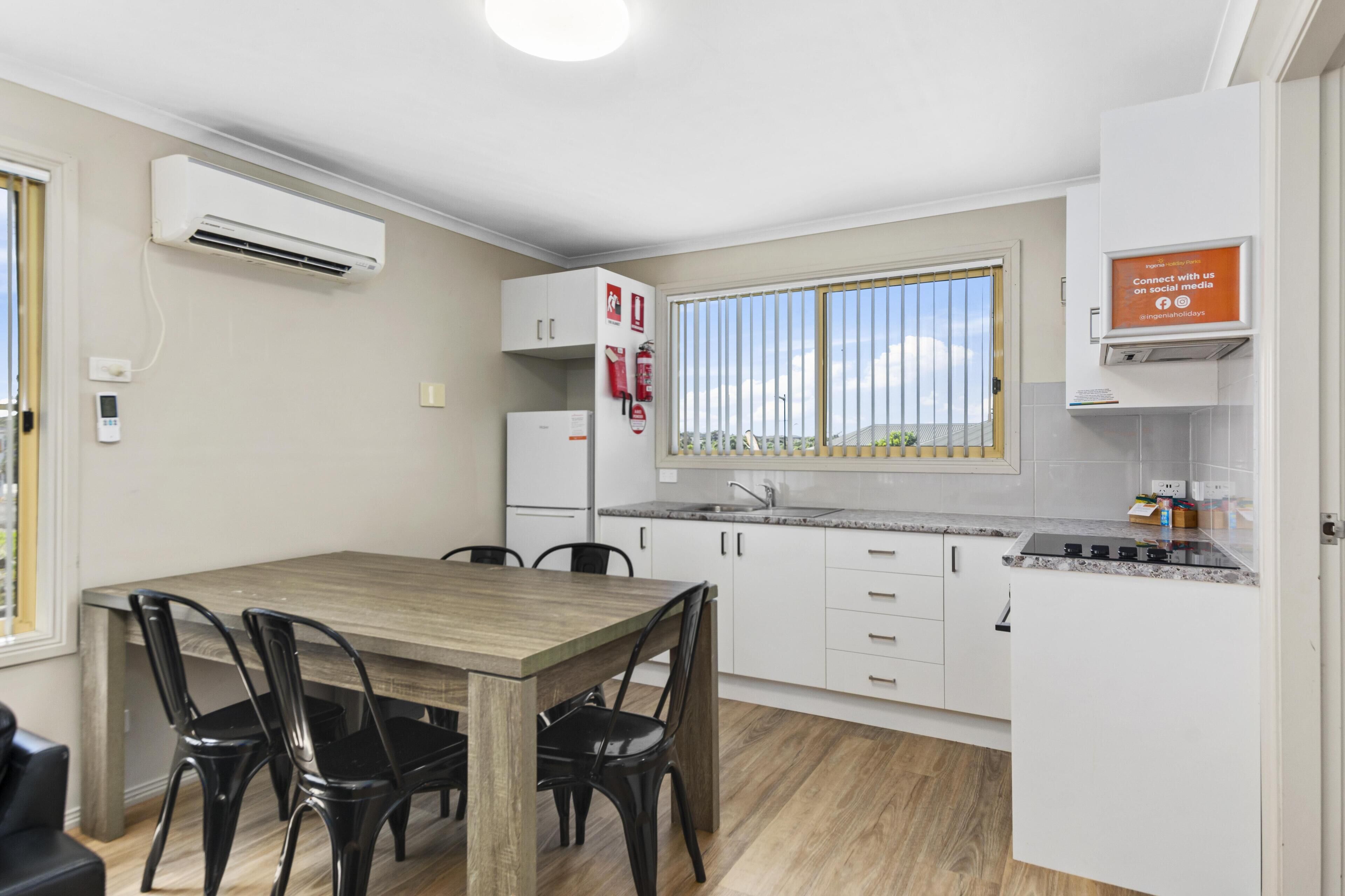 A modern kitchen with white cabinets, a wooden dining table, and black chairs.