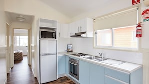 Una cocina moderna con armarios blancos, un refrigerador de acero inoxidable, un microondas, un horno y un lavaplatos.
