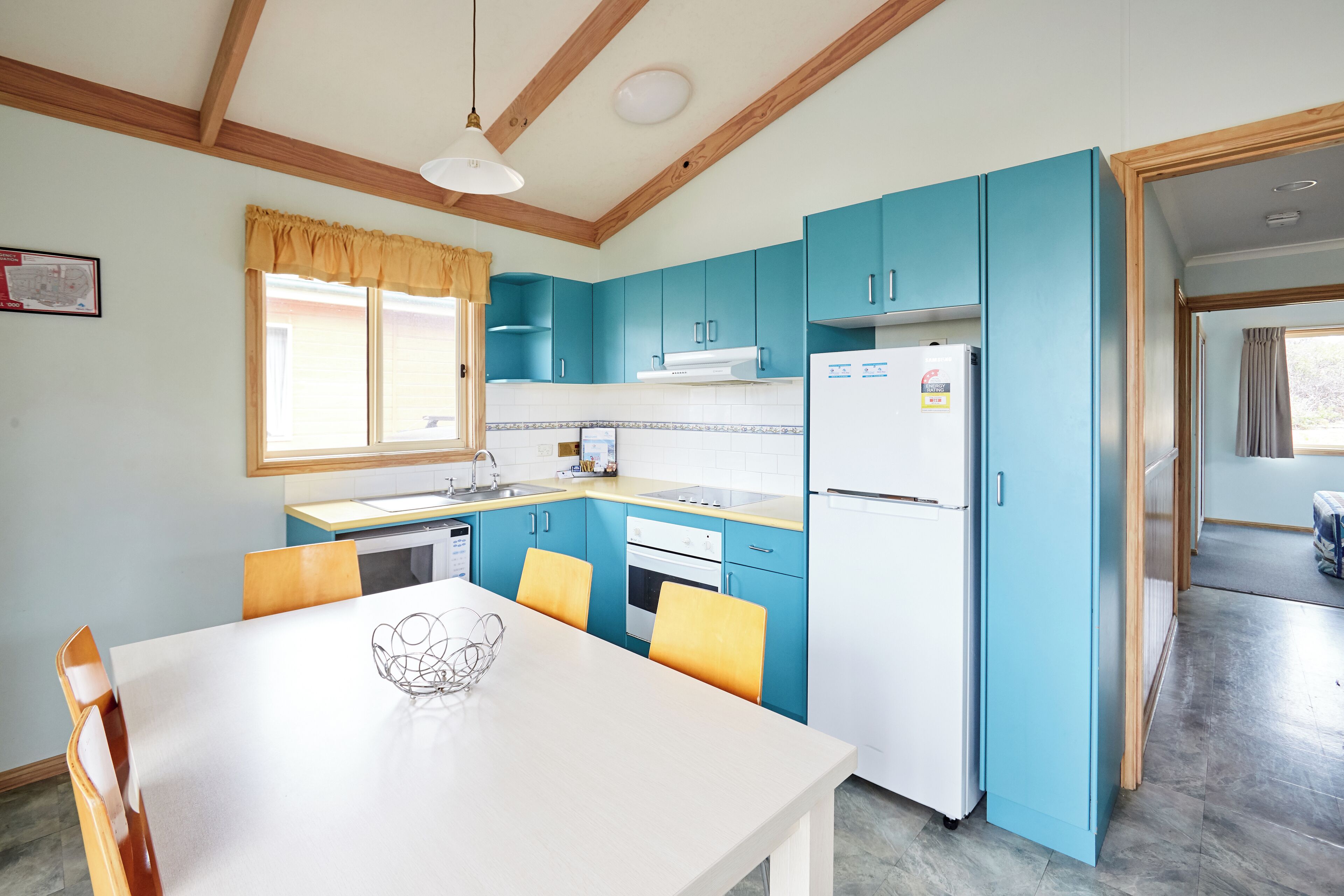 A kitchen with blue cabinets, a white refrigerator, and a dining table with chairs.