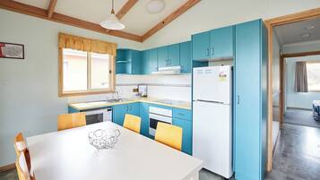 A kitchen with blue cabinets, a white refrigerator, and a dining table with chairs.