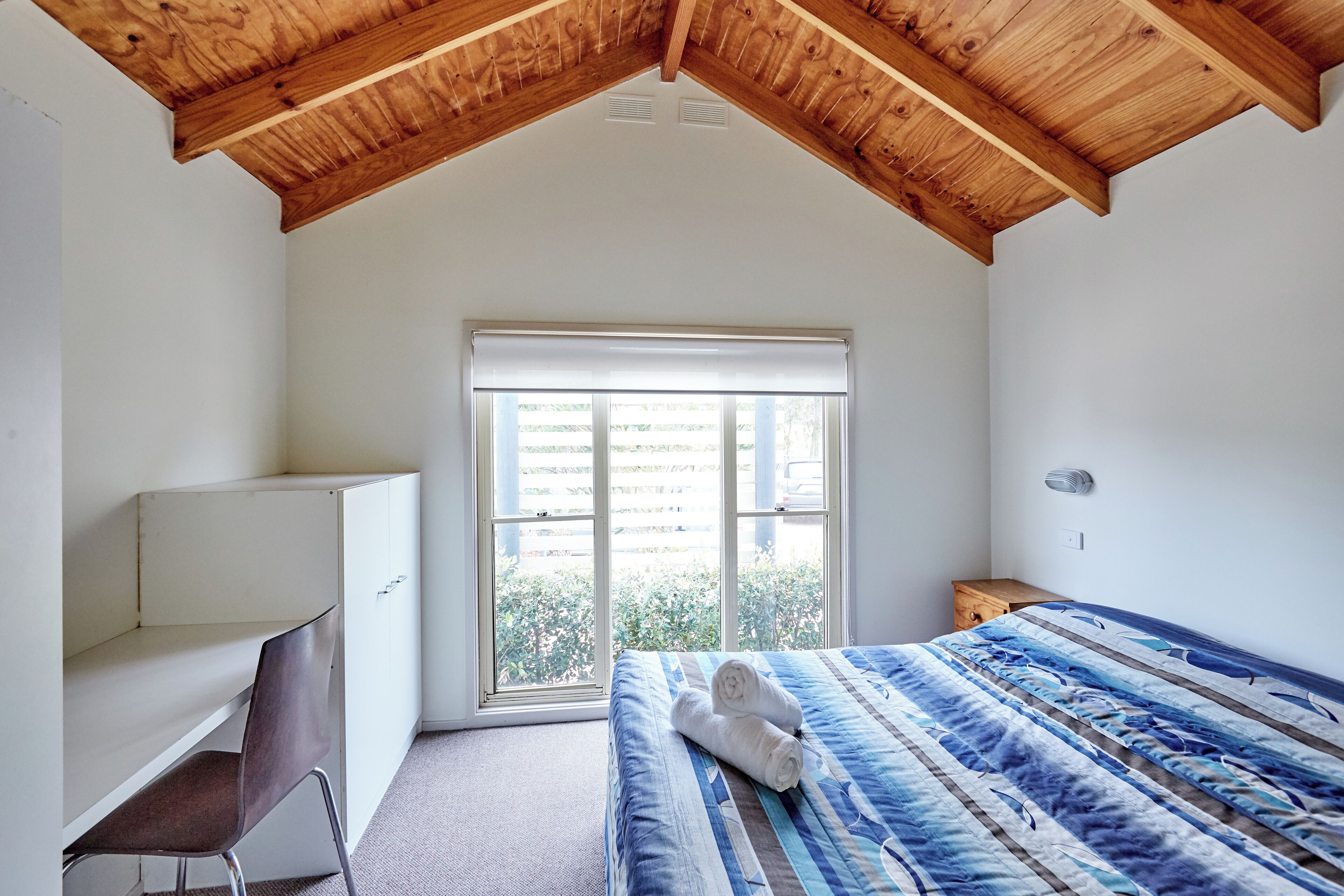 Ein Schlafzimmer mit einem Bett, einem Schreibtisch und einem Fenster.