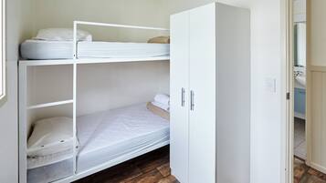 Ein Stockbett mit weißer Bettwäsche, ein Kleiderschrank mit silbernen Griffen und ein Holzboden.