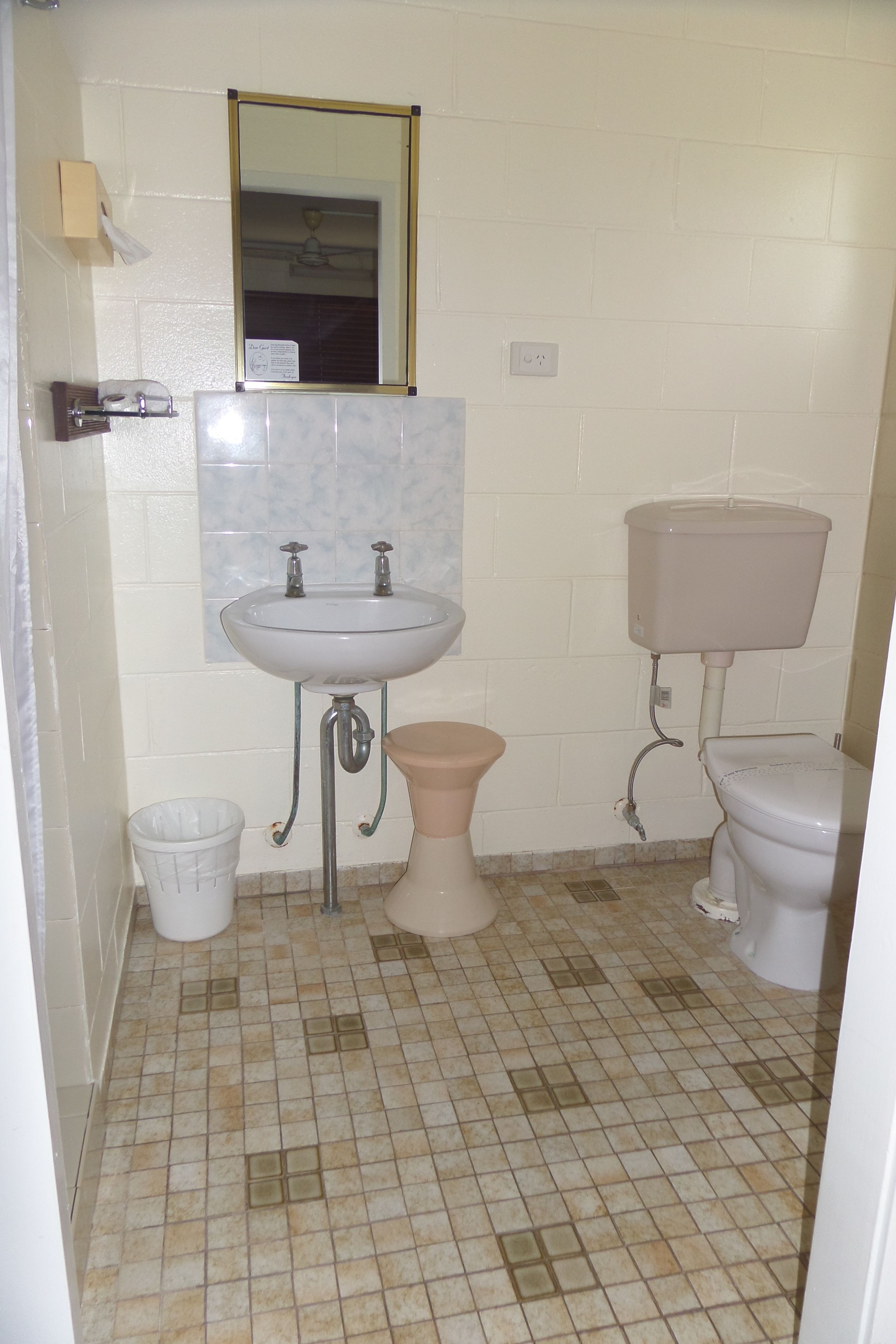 Un baño con lavamanos, inodoro y cubo de basura.