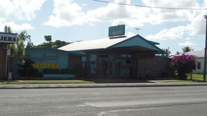 Um motel com placa, estacionamento e céu claro.