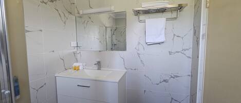 Un baño con lavamanos blanco, espejo y paredes con diseño de mármol.