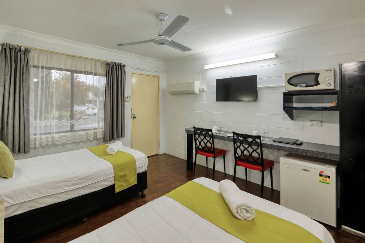 Een hotelkamer met twee bedden, een bureau, een televisie, een magnetron en een koelkast.