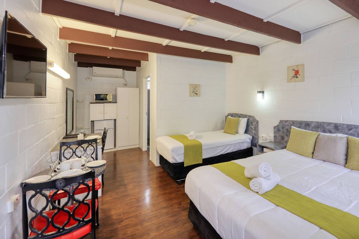 Een hotelkamer met twee bedden, een klein keukenblok, een zithoek en een badkamer.