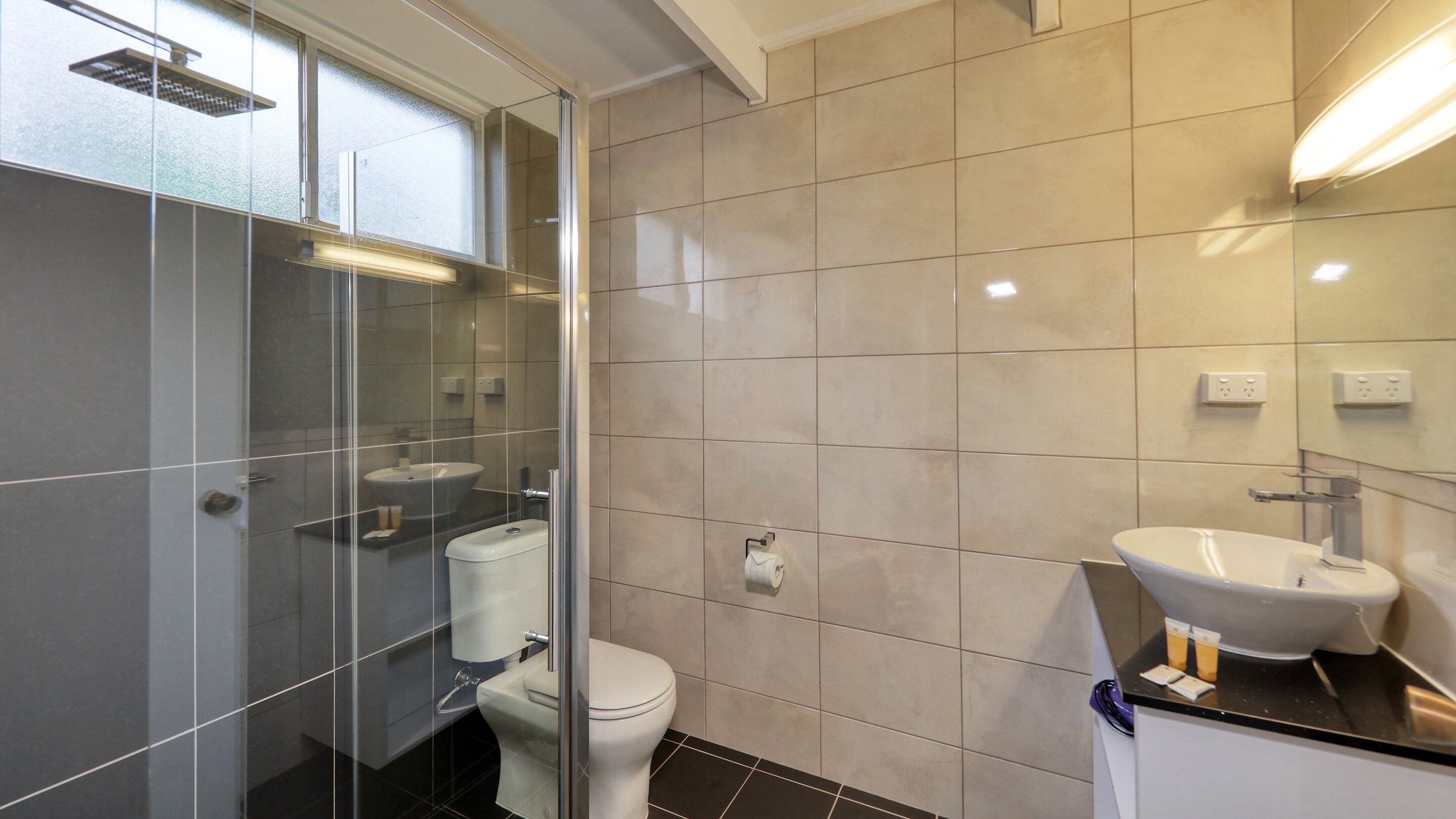 A modern bathroom with a glass shower enclosure, a toilet, and a sink.