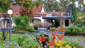 Un jardín con recepción, zona de estar al aire libre y un edificio con tejado rojo.