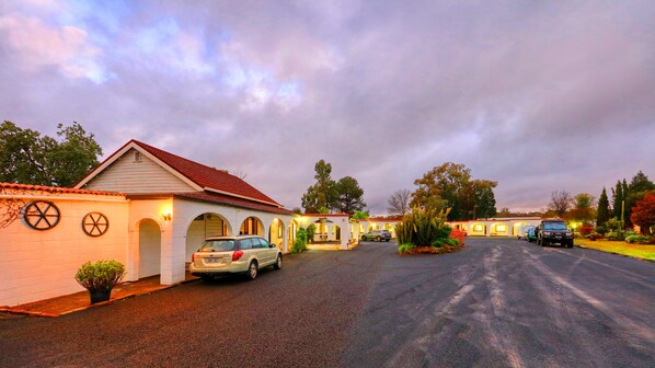 A motel with multiple rooms, a parking area, and a garden with cacti.