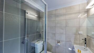 Et moderne badeværelse med brusekabine i glas, toilet og vask.