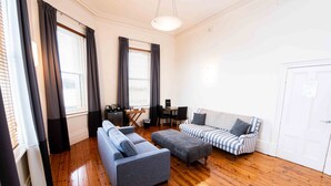 Un salon moderne avec un canapé gris, un canapé à rayures et un plancher en bois.
