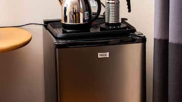 Une petite cuisine équipée avec un réfrigérateur en acier inoxydable, une bouilloire et une machine à café placés sur le plan de travail.
