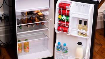 Un refrigerador abierto con diversas bebidas y aperitivos.