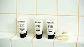 Three bottles of Biolgy hair care products on a tiled shelf.