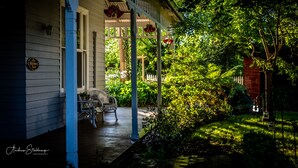 A porch with a bench, a sign, and a garden with a fence. - Heytesbury House (Cobden)