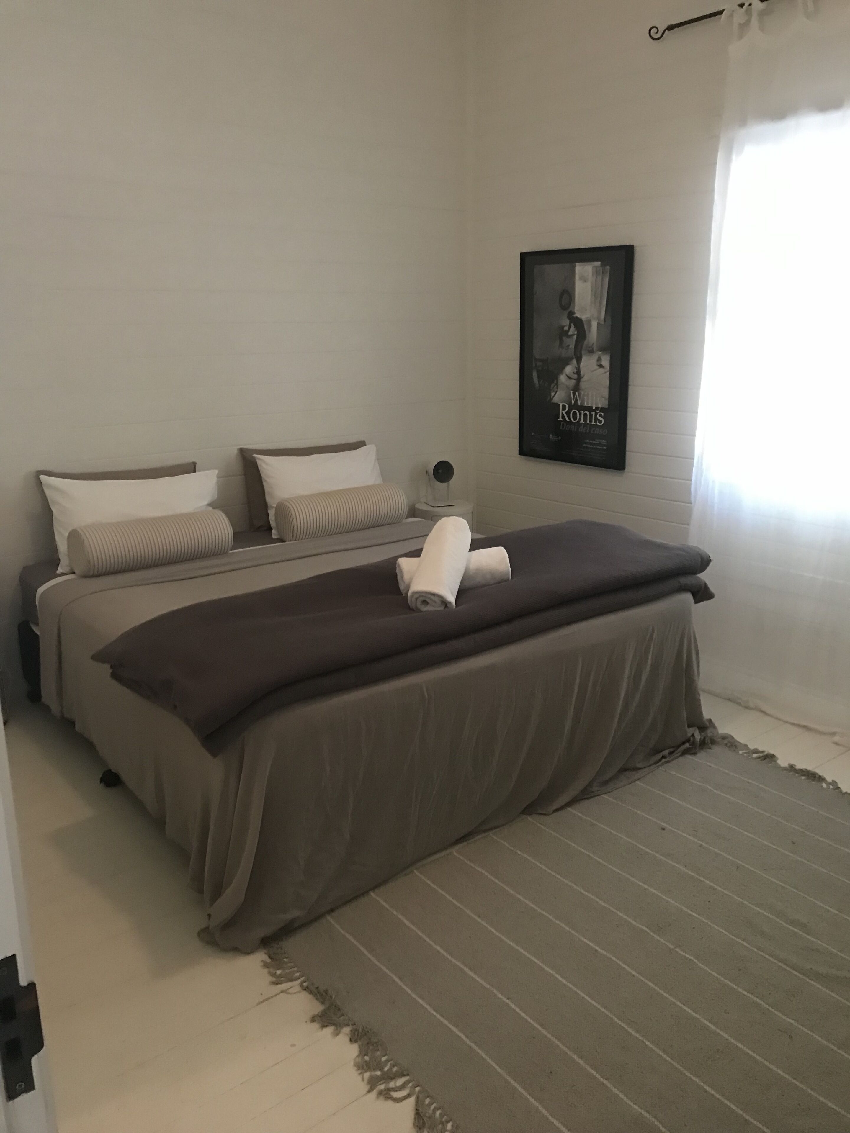A bedroom with two beds, a framed picture on the wall, and a window with curtains.