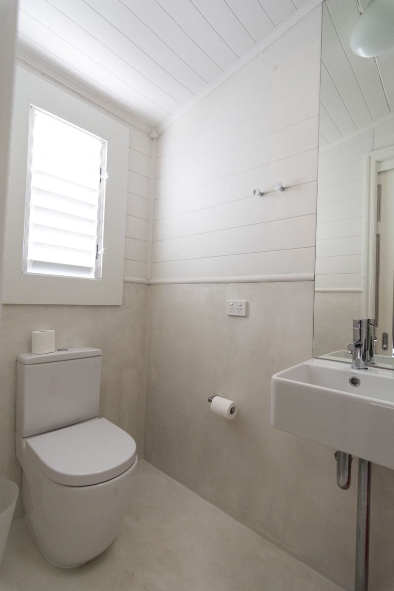 A bathroom with a toilet, a sink, and a window.