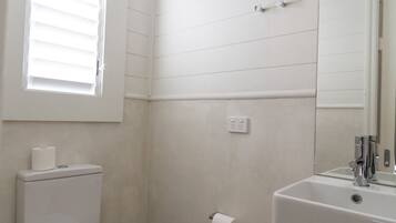 A bathroom with a toilet, a sink, and a window.
