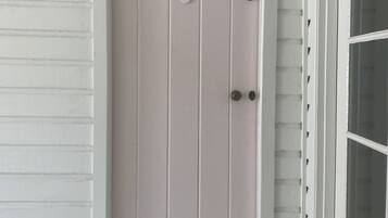 Una puerta blanca con el número 6, una ventana a la derecha y un suelo de madera.
