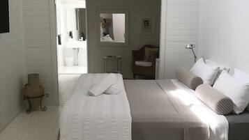 Un dormitorio con una cama grande, una mesita de noche, una lámpara, un espejo y vistas al baño.
